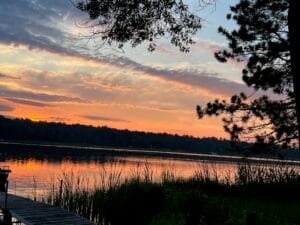 Sunrise reflecting over a calm lake at Heather’s family lake house, symbolizing stillness and clarity in decision-making.